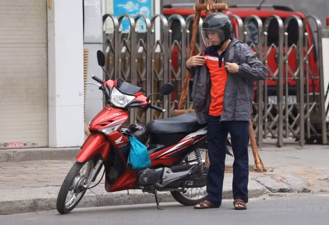 Người đàn ông dừng xe bên đường Tôn Đức Thắng để mặc thêm áo rét. Người đàn ông dừng xe bên đường Tôn Đức Thắng để mặc thêm áo rét.