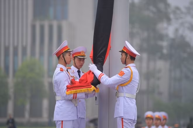Ba chiến sĩ tiến về cột cờ thực hiện nghi thức treo cờ rủ.