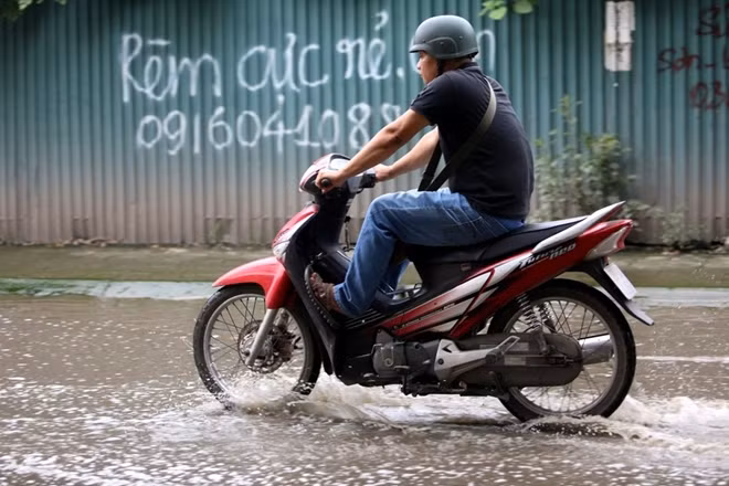 Nhiều người đi xe máy qua đây phải co chân cao lên để tránh nước bẩn bắn vào người.