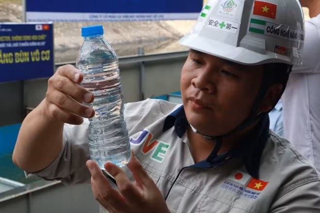Ông Nguyễn Tuấn Anh- Chủ tịch hội đồng quản trị công ty cổ phần cải thiện môi trường Nhật Việt mang mẫu nước từ bể xử lý lên để so sánh cả nước đóng chai.