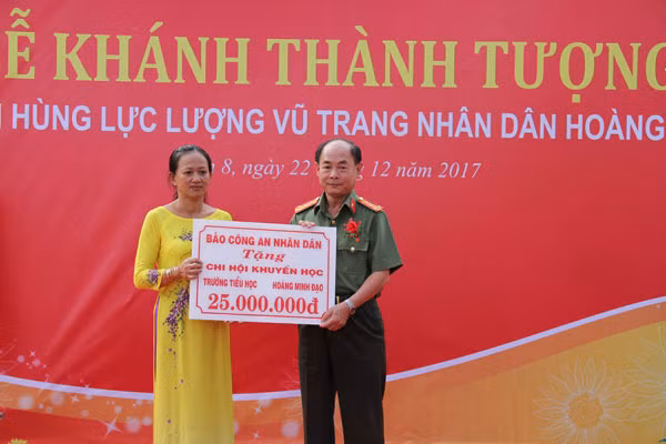 Đại tá Trần Kim Thẩm trao quà tặng của Báo CAND cho các em học sinh có hoàn cảnh khó khăn.