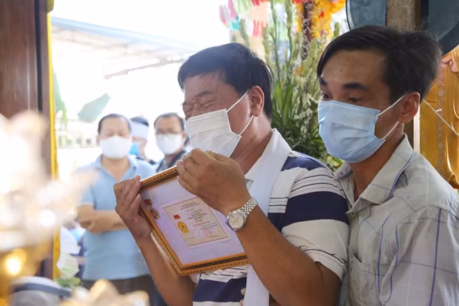 Ông Võ Xuân Tài nghẹn ngào ôm huy hiệu “Tuổi trẻ dũng cảm” của con trai.