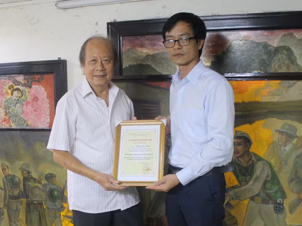Họa sĩ Phùng Dzi Thuần (bên trái) nhận Giấy chứng nhận của UBND TP Hà Nội.