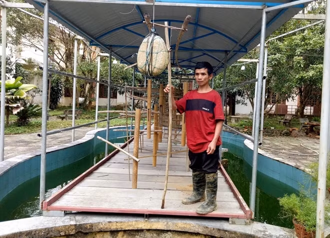 Nghệ nhân Hồ Văn Thập cùng bộ đàn nước trưng bày tại UBND huyện Nam Trà My.
