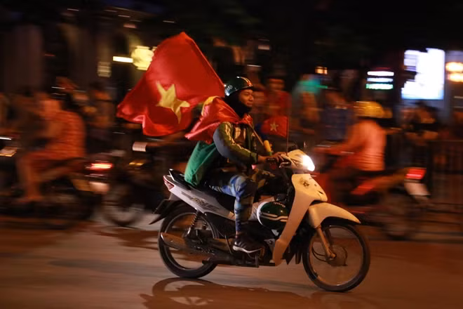 Một tài xế xe ôm công nghệ cũng tham gia "bữa tiệc đường phố". Chiến thắng của ĐTVN khiến nhiều người tạm thời bỏ qua những lo toan cuộc sống hàng ngày để hòa mình vào niềm vui chung của cả đất nước.