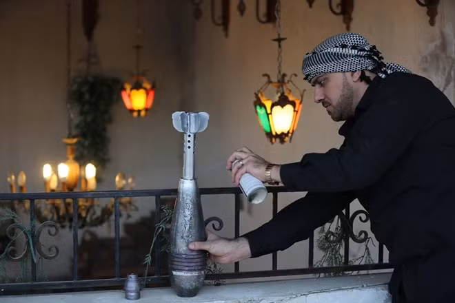 Akram Abu al-Faiz và quả đạn pháo cối chuẩn bị biến thành tác phẩm nghệ thuật.