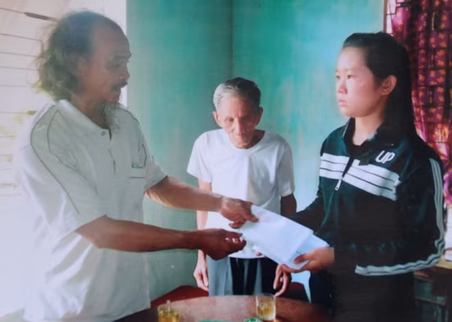Ông Bình trao tiền cho học sinh khó khăn.
