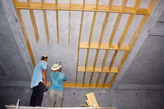 Một nhóm thợ lắp đặt khung gỗ bên trong một nhà nuôi chim yến.