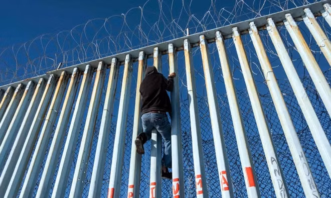 Một người di cư từ Trung Mỹ leo lên hàng rào biên giới Mỹ-Mexico ở Playas de Tijuana, bang Baja California, Mexico vào ngày 29-12-2018.