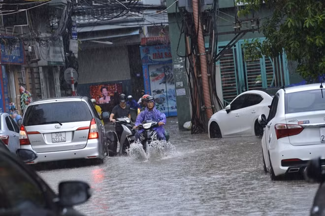 Trên phố Vương Thừa Vũ mưa biến đường thành "sông" gây khó khăn cho giao thông đi lại và ảnh hưởng không nhỏ đến việc buôn bán, kinh doanh.
