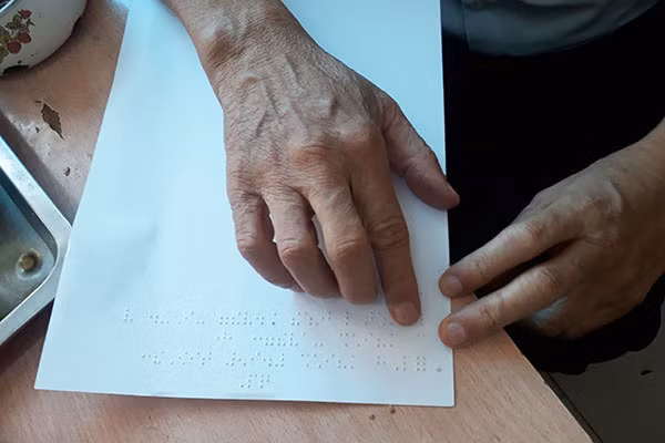 Đôi mắt đã mờ nên thầy Thắng phải đọc viết chữ nổi.