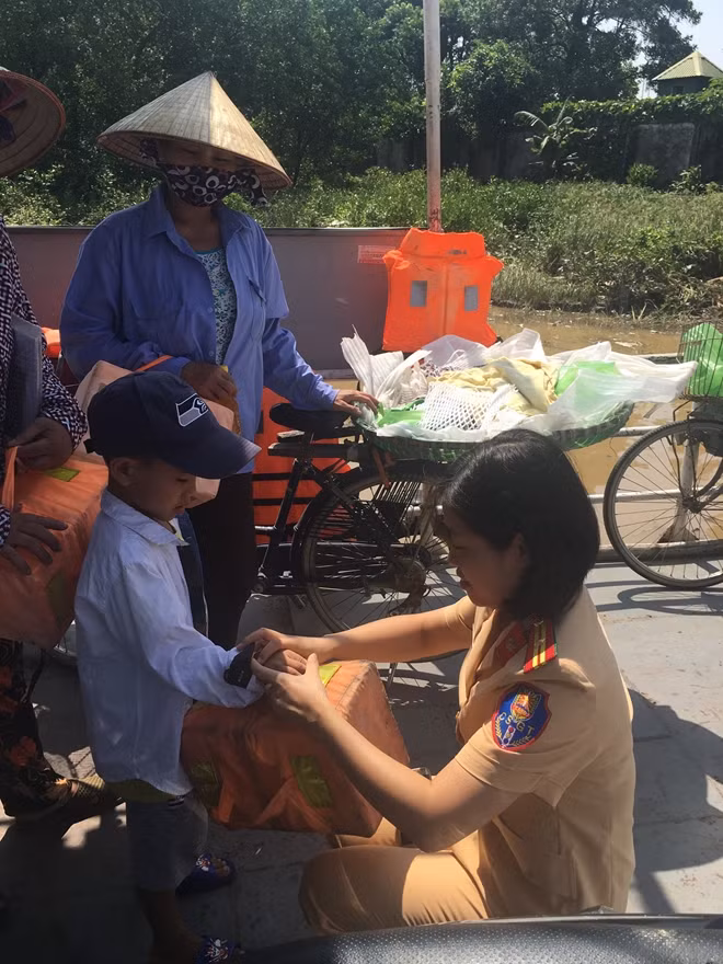 Cán bộ Cảnh sát đường thuỷ giúp cháu bé đeo công cụ nổi khi đi phà.