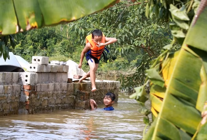 "Bể bơi bất đắc dĩ" của các em "cũng có khá nhiều trò vui". Trong ảnh một cậu bé đang "biến" bờ tường thành chỗ nhảy cầu.
