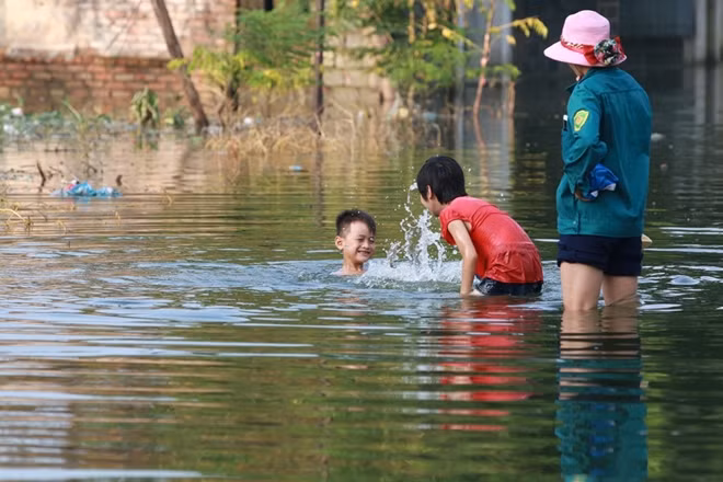 Trong khi đó hai em nhỏ này lại được gia đình đưa ra một chỗ nước nông để tập bơi.