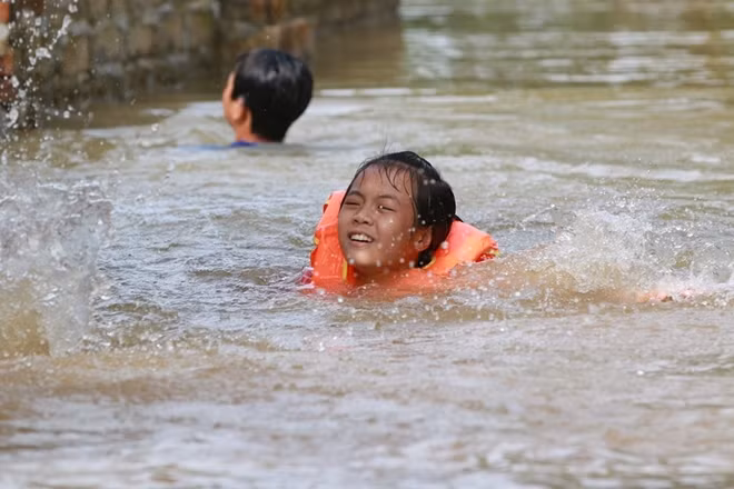 Một cô bé đang cố gắng tập bơi trong dòng nước lụt.