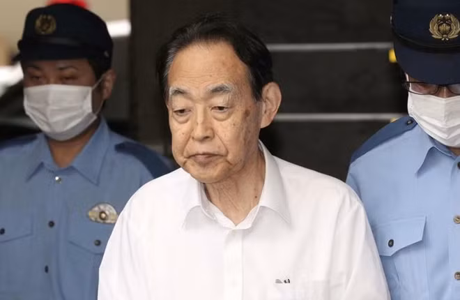 Cảnh sát áp giải Hideaki Kumazawa (áo trắng) đến gặp công tố viên.