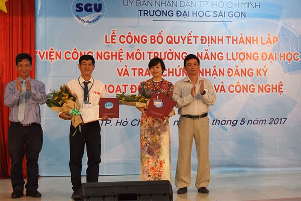PGS.TS Nguyễn Kỳ Phùng, Phó Giám đốc Sở KH&CN TP Hồ Chí Minh và PGS.TS Phạm Hoàng Quân cùng trao quyết định và tặng hoa chúc mừng lãnh đạo Viện CNMT&NL Đại học Sài Gòn.
