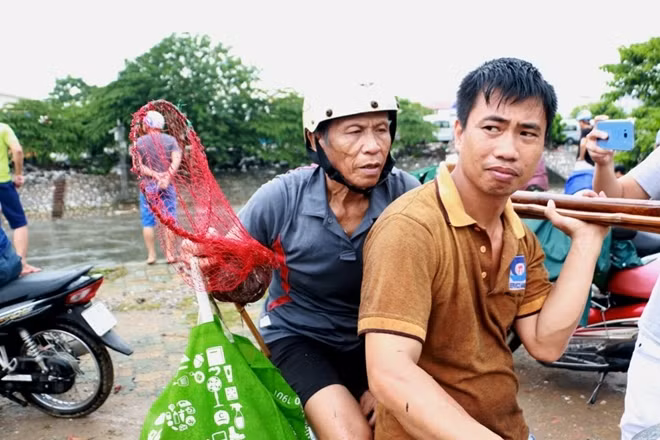 Bác Nguyễn Vũ Minh (ngồi sau, 73 tuổi) cùng con trai đã cất vó tại sông Kim Ngưu từ đêm qua đến sáng nay (4-8). Bác Minh cho biết lượng cá đánh được tối hôm qua nhiều hơn bởi trời mưa lớn...