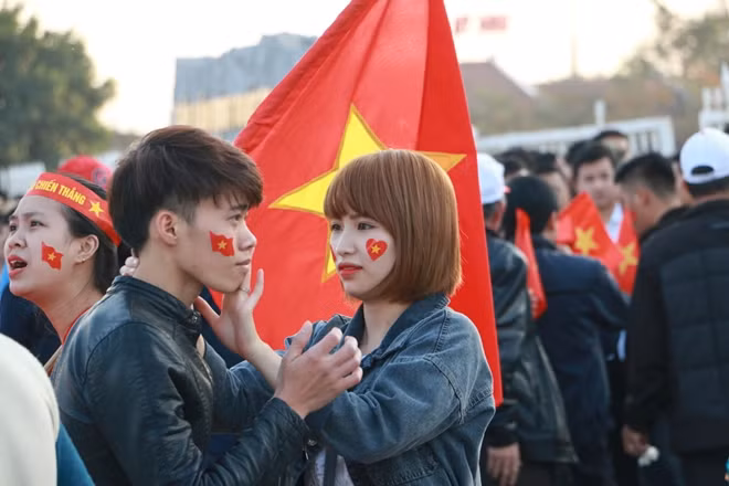 Những cổ động viên đang dán quốc kỳ lên má.