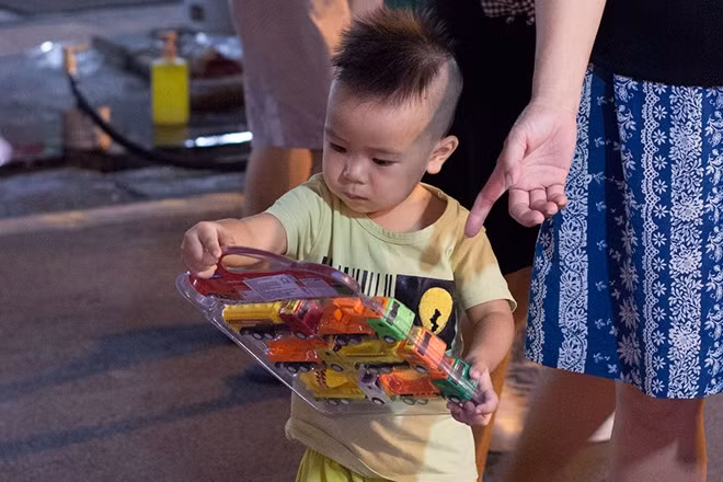 Một cậu bé tỏ ra lạ lẫm với những chiếc ô tô đồ chơi được bố mua cho.