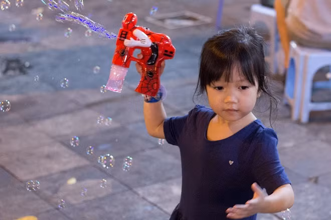 Còn cô bé này lại đang nghịch ngợm với khẩu súng bắn bong bóng của mình.