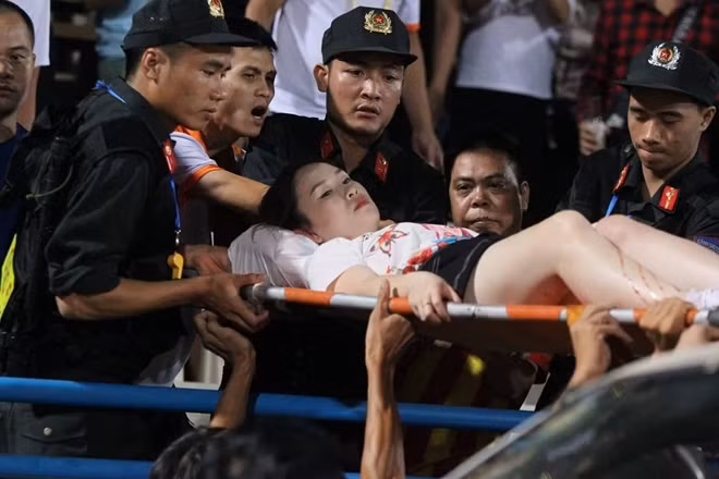 CĐV nữ phải rời sân bằng cáng sau khi bị thương vì pháo sáng.