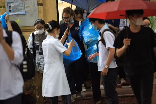 Nhiều thí sinh không mang theo ô được phát áo mưa nhằm tránh bị ướt khi rời phòng thi.