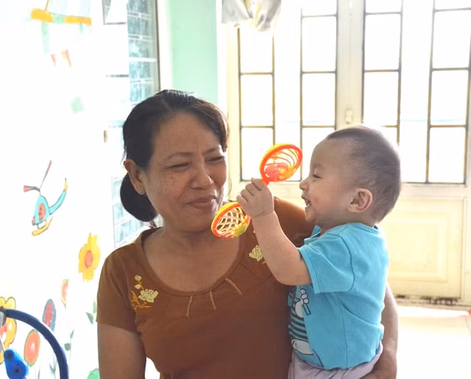 Bà bảo mẫu với cháu bé trong mái ấm tình thương.