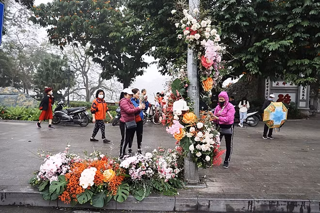 Sáng 8/3, người dân quanh khu vực hồ Hoàn Kiếm bất ngờ khi những cột đèn bỗng biến thành cột hoa tươi rực rỡ sắc màu. Những khóm hoa được trang trí tỉ mỉ, uốn lượn quanh thân cột, tạo thành điểm check-in độc đáo trong ngày Quốc tế Phụ nữ. Ảnh: Ngọc Thành.