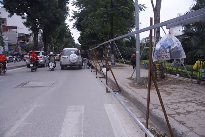 Các công nhân đang dựng hàng rào tôn ngăn cách giữa đường và công trường thi công.