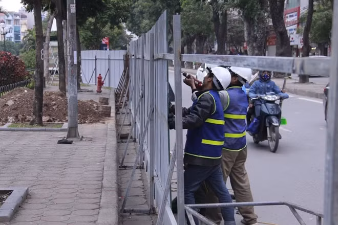 Các công nhân đang dựng hàng rào tôn ngăn cách giữa đường và công trường thi công.
