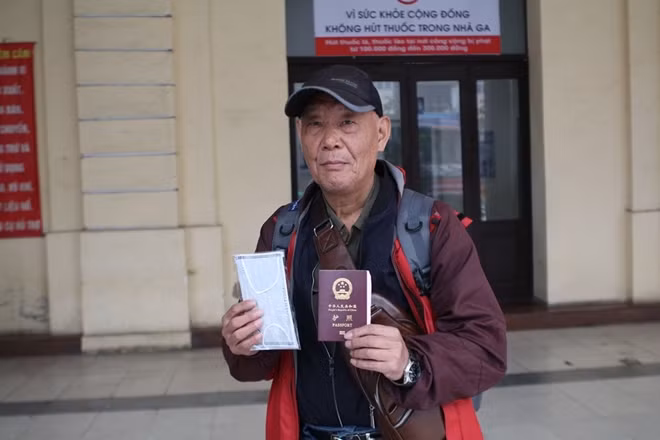 Một vị khách người Trung Quốc và chiếc khẩu trang được phát miễn phí từ chương trình tại điểm phát ở Ga Hà Nội.
