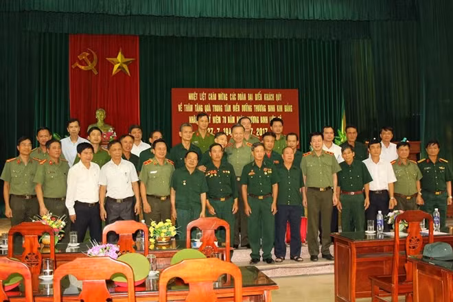 Bộ trưởng Tô Lâm, ông Nguyễn Đình Khang và các đại biểu chụp ảnh lưu niệm cùng các thương binh tại Trung tâm điều dưỡng thương binh Kim Bảng.