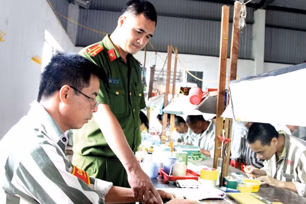 Trung tá Lê Ngọc Quỳnh hướng dẫn phạm nhân tại xưởng sản xuất.