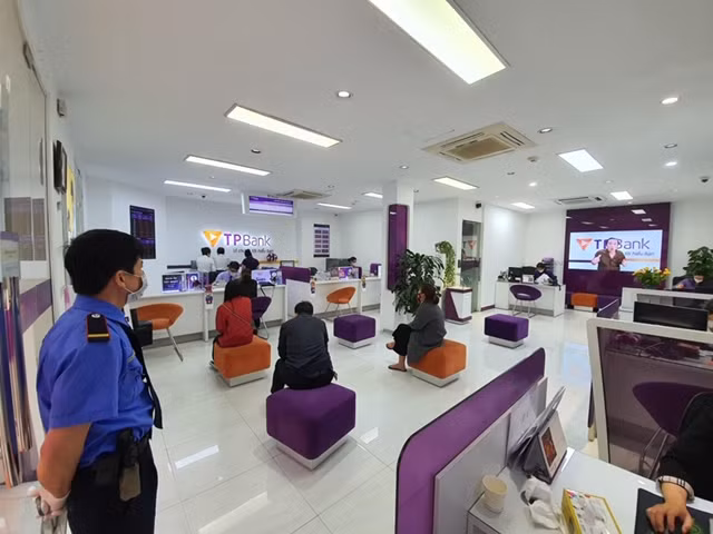 Khách hàng đứng xếp hàng tại các điểm đã được đánh dấu trước khi chờ giao dịch tại TPBank. Khách hàng đứng xếp hàng tại các điểm đã được đánh dấu trước khi chờ giao dịch tại TPBank.