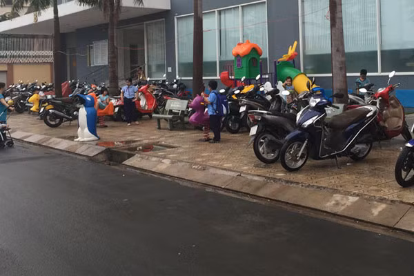 Xe máy đậu tràn ra vỉa hè ở một tòa nhà cao tầng.