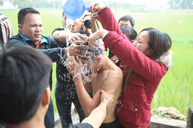 Sau khi làm lễ ở đình, 3 thanh niên được hộ tống ra khu vực giếng nước để gội rửa sạch.