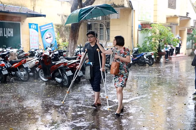 Rất nhiều em không chuẩn bị áo mưa hay ô. Lúc này một số giám thị và nhân viên của nhà trường cầm ô che mưa đưa các sĩ tử rời phòng thi.