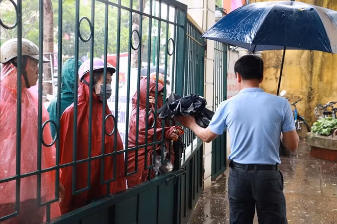 Một số người khác nhờ giám thị chuyển áo mưa cho con em đang ở trong trường.