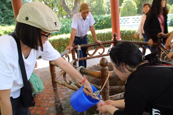 Chị Nhàn cùng bạn xách nước rửa mặt tại giếng cổ trong khuôn viên Bảo tàng Quang Trung.