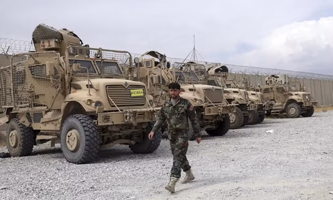 Binh sĩ Afghanistan đi ngang qua hàng thiết giáp quân đội Mỹ bỏ lại căn cứ Bagram.