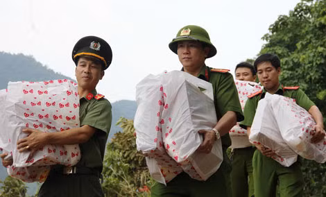Đoàn công tác của Báo CAND và Công an huyện Bố Trạch bốc hàng cứu trợ xuống đò để qua sông làm hỗ trợ bà con Trằm Mé.