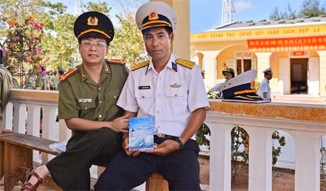 Thượng tá, nhà thơ Phạm Khải (bên trái) tặng sách “Thêm một lần biển gọi” cho đại diện cán bộ, chiến sĩ đảo Sơn Ca, quần đảo Trường Sa (sáng 23-4-2016). Ảnh: Đinh Thành Đức.