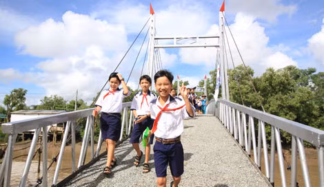 Những em học sinh của trường tiểu học Hiệp Vinh vui mừng đi trên cây cầu mới.