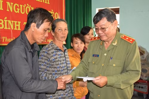 Trung tướng Lê Ngọc Nam thay mặt Báo CAND và nhà tài trợ tặng quà bà con.