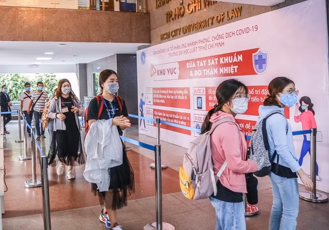 Sinh viên trường đại học Luật TP Hồ Chí Minh thực hiện đeo khẩu trang khi ra vào cổng trường và tuân thủ ý thức sát khuẩn phòng chống dịch COVID-19.