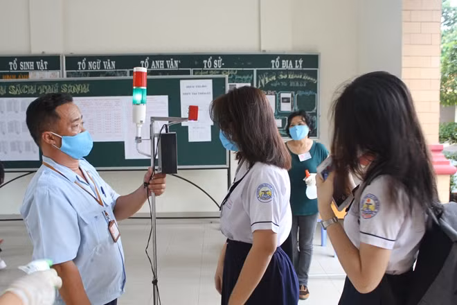 Đo thân nhiệt cho thí sinh trong khuôn viên trường thi tại THPT Thủ Thiêm, quận 2.