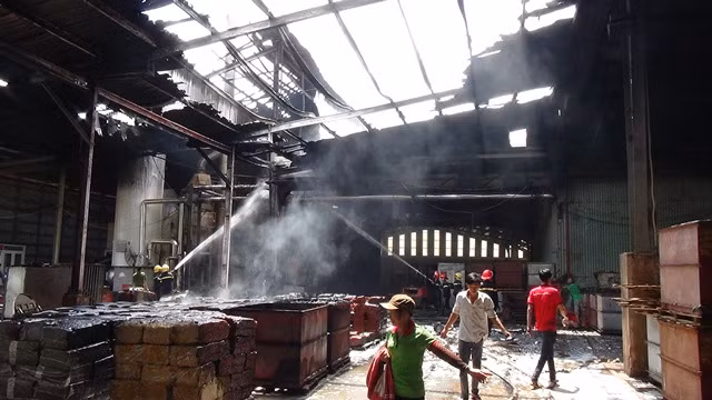 Phần mái nhà xưởng bị cháy rụi và một số kiện hàng mủ cao su được đưa ra khỏi khu vực cháy