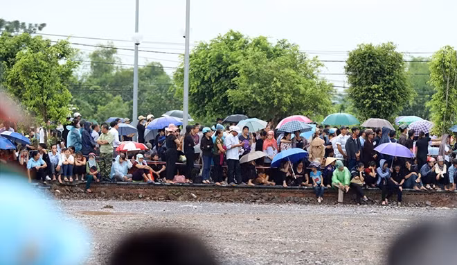 Người dân ngồi đợi 2 bên đường.