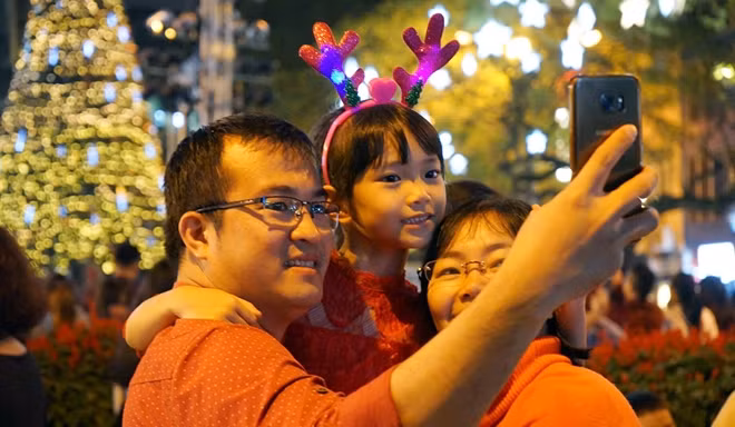 Một gia đình đưa con đi chơi đêm Noel